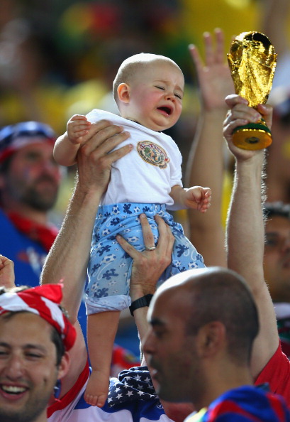 A young fan is held up next to a replica of the World Cup trophy during the 2014 FIFA World Cup Brazil Group G match between Ghana and the United States (credit: Michael Steele/Getty Images)